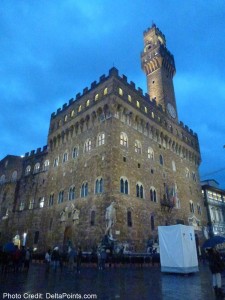 a large stone building with a clock tower with Palazzo Vecchio in the background